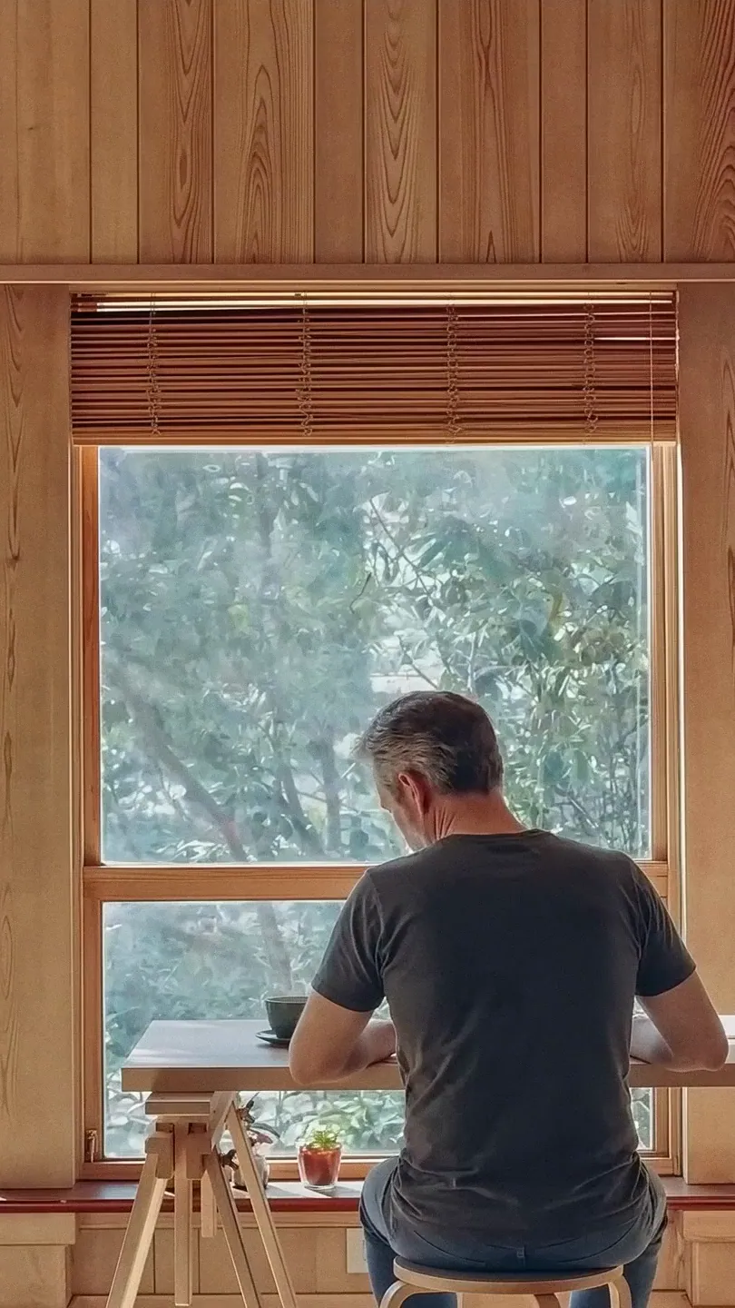 A man working at a desk by a large window